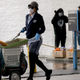 A U.S. Postal Service (USPS) worker wears a mask and gloves while delivering mail, as recipients (R) stand with food they received at a Food Bank distribution for those in need, as the coronavirus pandemic continues on April 9, 2020 in Van Nuys, California.